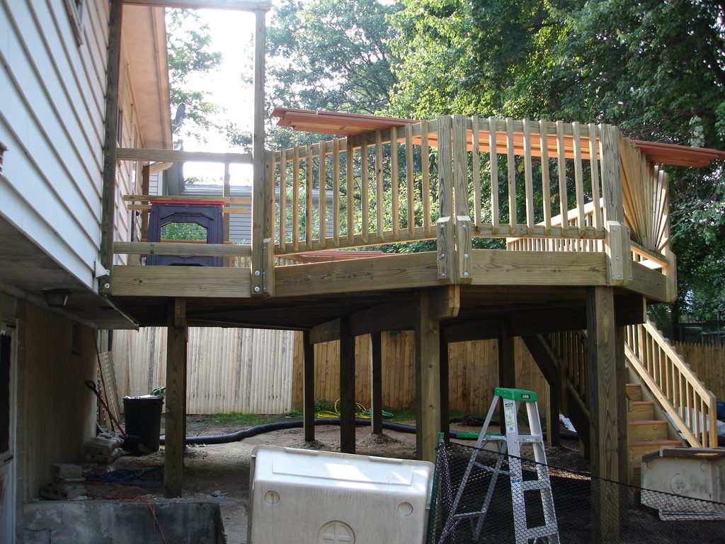 A newly framed raised timber deck with fresh railings and stairs beside a house